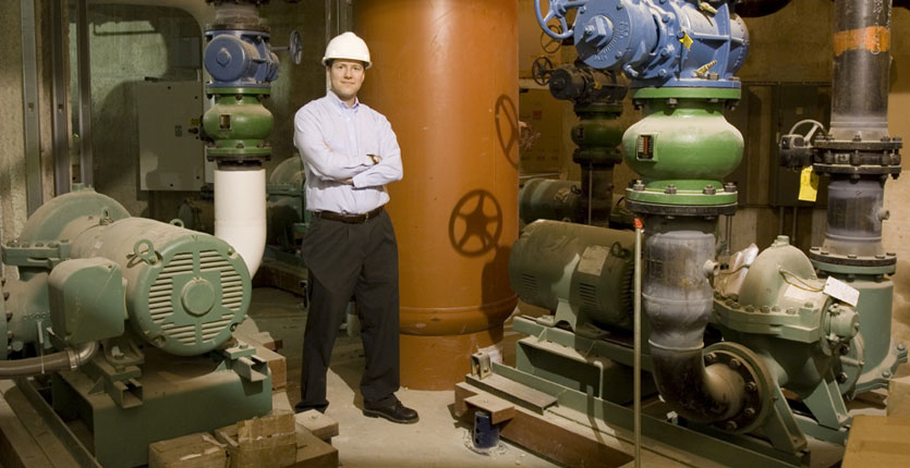 Smiling maintenance worker standing next to a tuned chiller